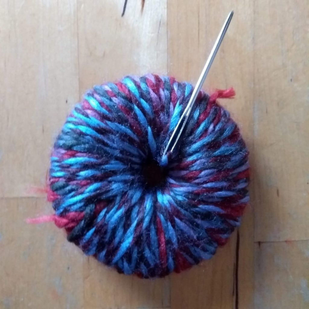 threading yarn to make pom pom