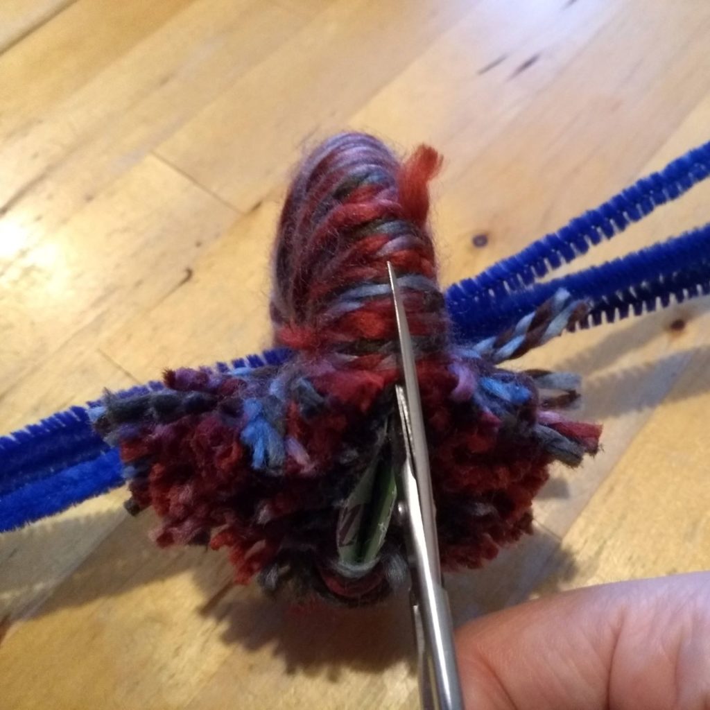 cutting strands of yarn to make pom pom