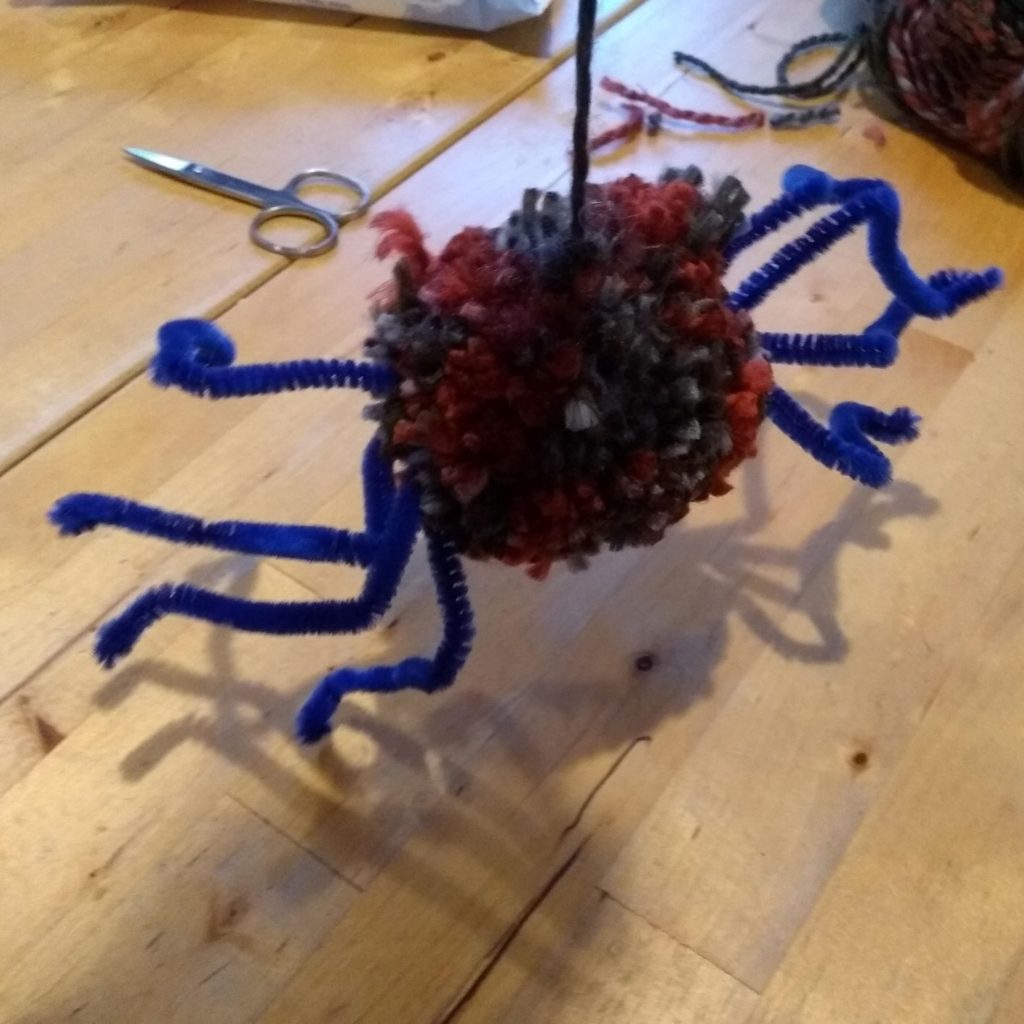 pom pom spider held by yarn used to make pom pom