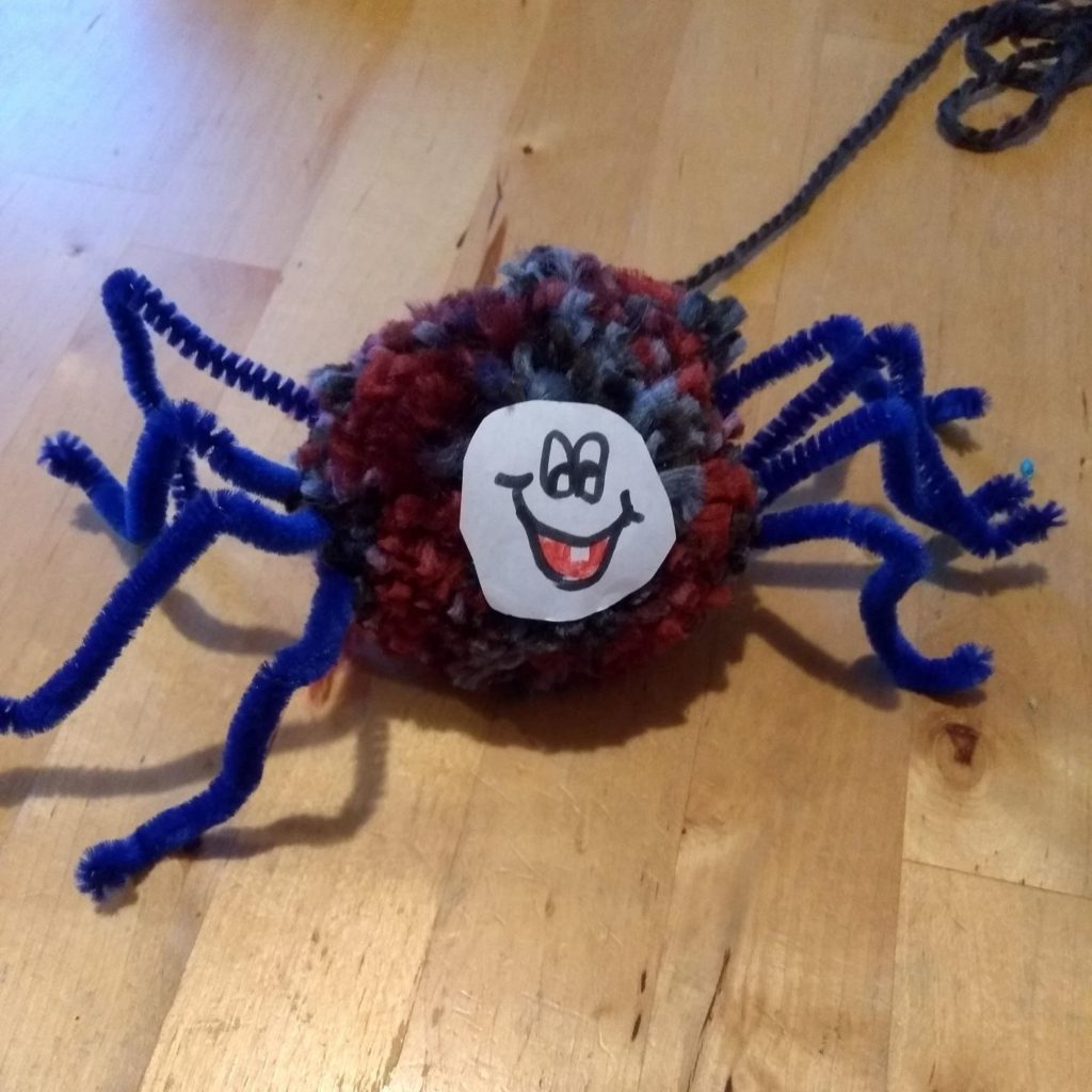 using a sticker as a face for a pom pom spider