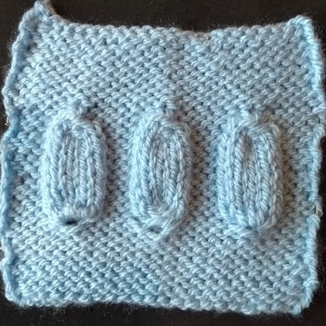 A knitted square swatch containing a row of three different 1 to 5 increases.