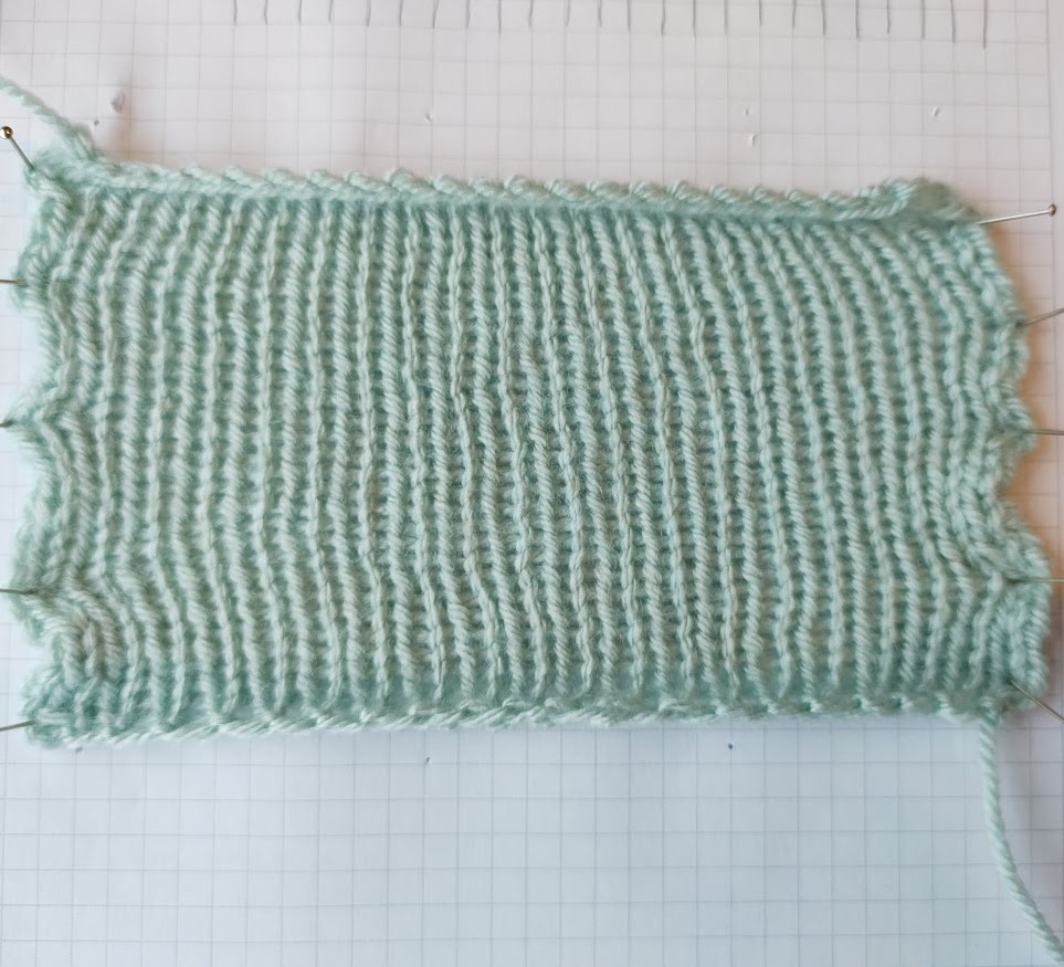 a light green 10 by 10 cm swatch of stocking stitch, stretched sideways as far as it will go to create a rectangular shape.